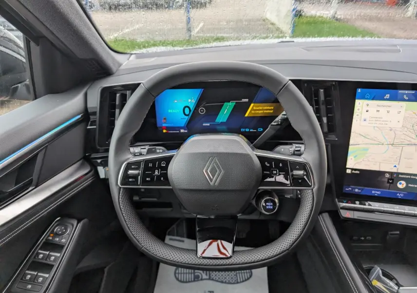 Vue intérieure centrée sur le volant noir du Renault Austral 2025 avec tableau de bord numérique et écran tactile latéral.