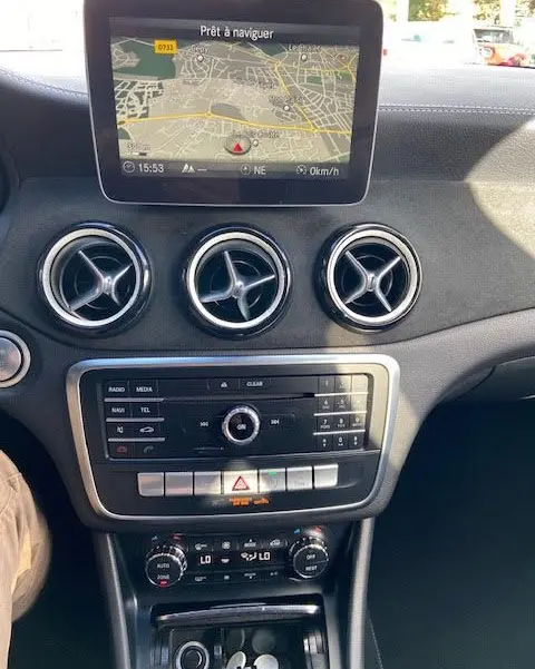 Vue intérieure du tableau de bord d'une Mercedes CLA Shooting Brake 200D WhiteArt Edition avec écran de navigation et aérateurs ronds chromés.