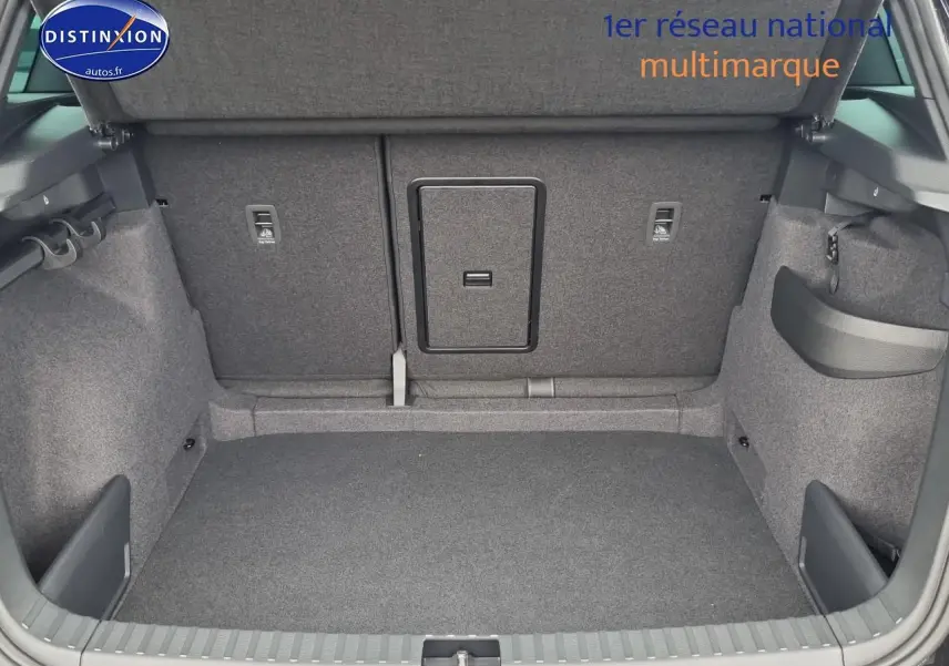 Coffre ouvert vu de l'arrière d'un Skoda Karoq noir 2025, montrant l'espace de chargement et la trappe à skis centrale.