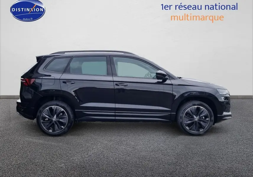 Vue de profil côté gauche d'un Skoda Karoq noir 2025 avec jantes alliage et barres de toit visibles.