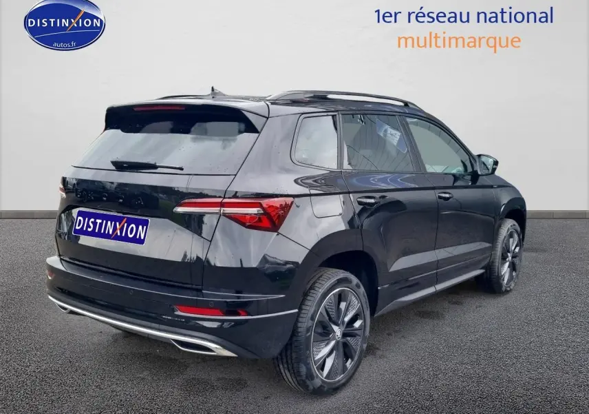 Vue 3/4 arrière droite d'un Skoda Karoq noir 2025 avec jantes alu et barres de toit visibles.