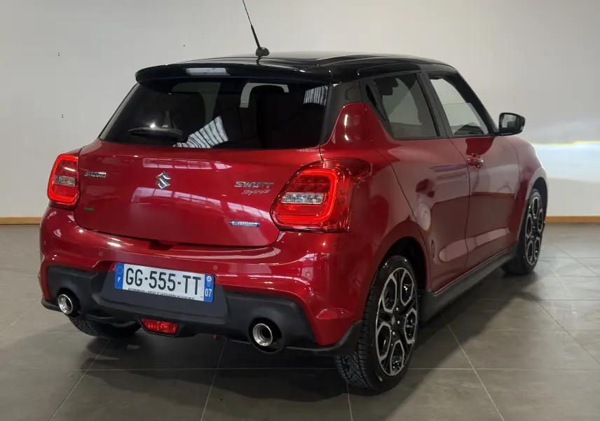 Vue 3/4 arrière droite de la Suzuki Swift Sport rouge 2022 avec toit noir et double sortie d’échappement chromée.