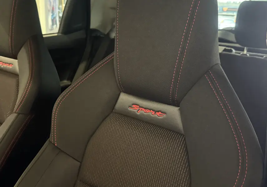 Gros plan sur le siège avant droit noir avec surpiqûres rouges et logo Sport rouge du Suzuki Swift Sport 2022.