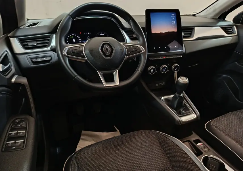 Vue intérieure avant du Renault Captur 2024 gris foncé, volant multifonctions et écran tactile vertical au centre.