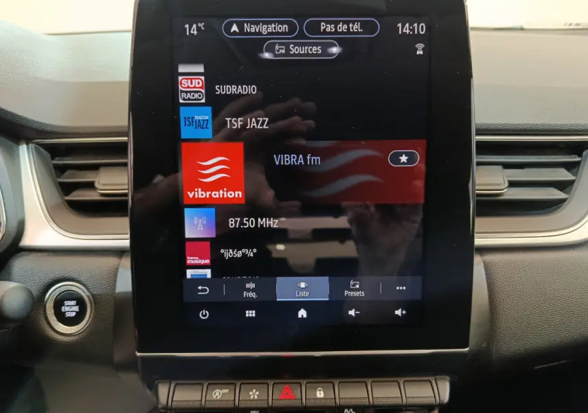 Vue rapprochée de l’écran tactile central du Renault Captur 2024 affichant les stations radio, avec bouton démarrage à gauche.