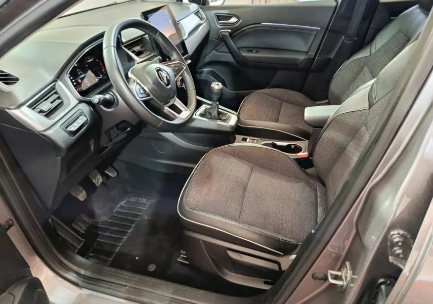 Vue intérieure côté conducteur du Renault Captur gris foncé 2024, volant multifonctions et écran tactile central visible.