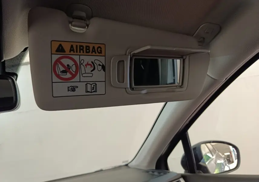 Détail intérieur du pare-soleil côté conducteur avec miroir et avertissement airbag dans un Renault Captur gris foncé.
