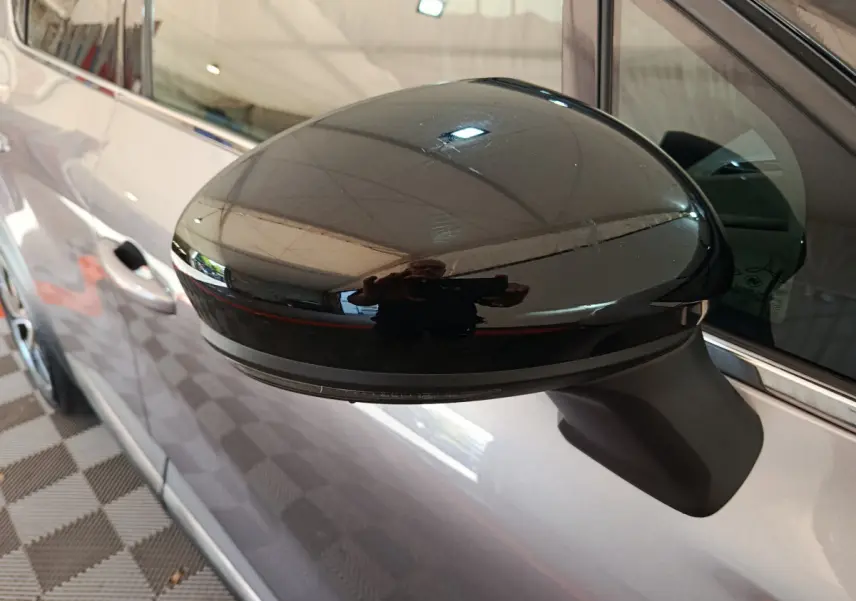 Gros plan sur le rétroviseur côté gauche noir brillant du Renault Captur gris foncé 2024, vue latérale partielle.