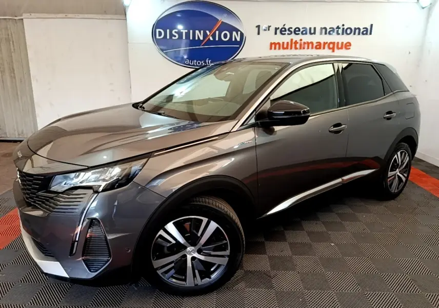 Peugeot 3008 gris foncé en 3/4 avant droit, avec jantes alliage et feux LED distinctifs, en intérieur showroom.