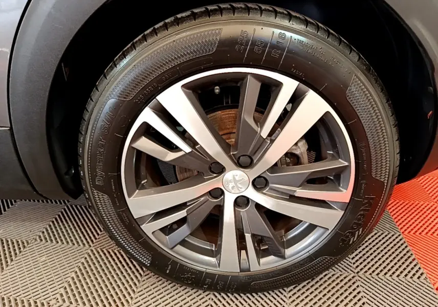 Gros plan sur la roue avant droite du Peugeot 3008 gris foncé, mettant en valeur la jante alliage au design moderne.