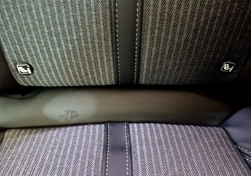 Détail de la banquette arrière gris foncé du Peugeot 3008 hybride, avec surpiqûres bleues et logos Isofix visibles.
