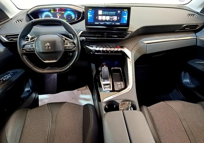 Intérieur Peugeot 3008 hybride 2022 vu de face, tableau de bord noir avec écran tactile central et volant compact cuir.
