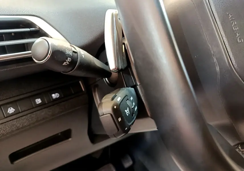 Gros plan sur les commandes au volant en cuir noir du Peugeot 3008 gris foncé, version hybride rechargeable 2022.