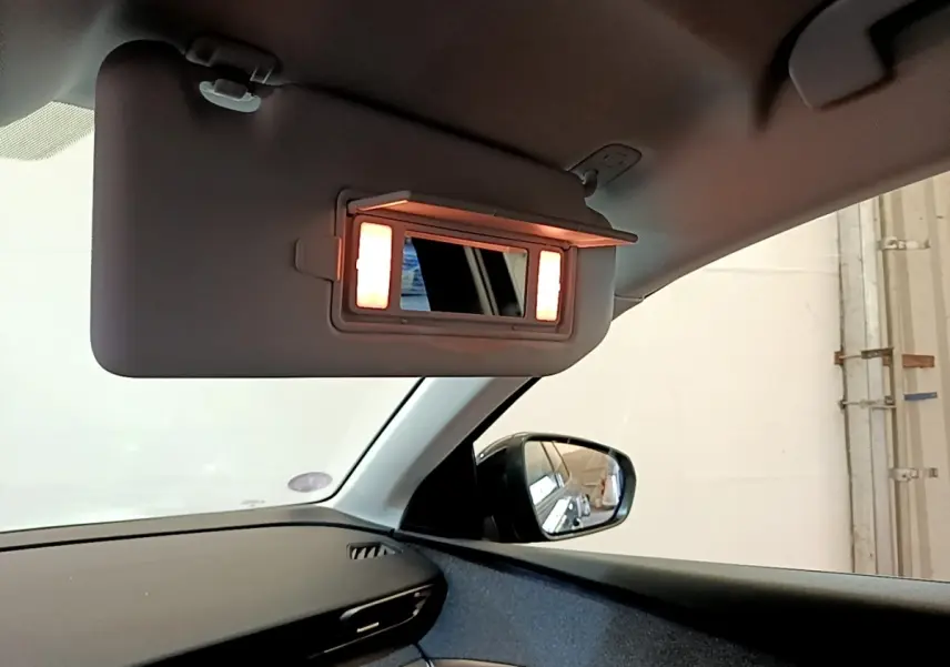 Miroir de courtoisie éclairé sur pare-soleil côté conducteur dans l’habitacle d’un Peugeot 3008 gris foncé.