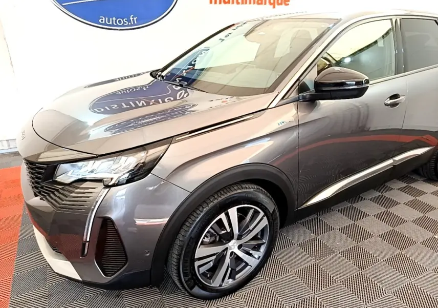 Peugeot 3008 hybride gris foncé en 3/4 avant droit, avec jantes alliage et phares LED allumés.