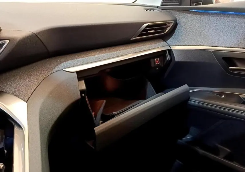 Intérieur Peugeot 3008 2022, vue côté passager, boîte à gants ouverte avec tableau de bord gris foncé et noir.