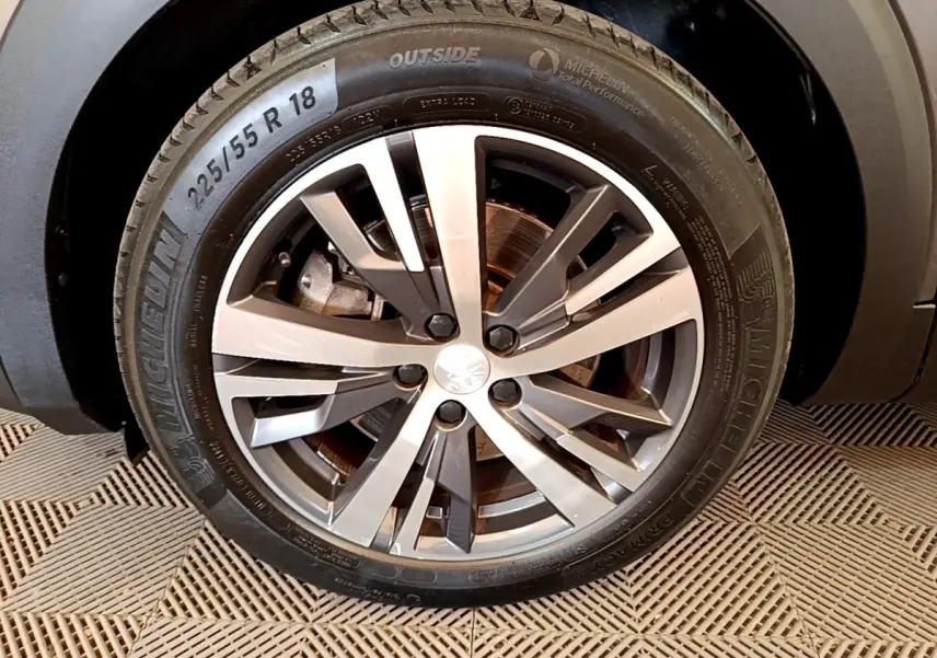 Gros plan sur la roue avant droite du Peugeot 3008 gris foncé, avec jante alliage moderne et pneu Michelin.