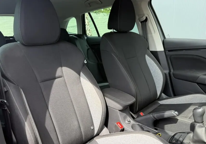 Vue intérieure des sièges avant tissu noir et gris avec accoudoir central et levier de vitesse manuel d'une Skoda Scala 2025.
