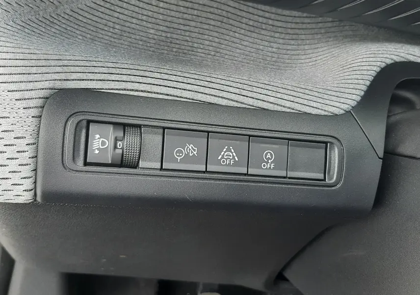 Gros plan sur les commandes de réglage des phares et aides à la conduite de la Citroën C3 1.2 Turbo 2025, intérieur noir.