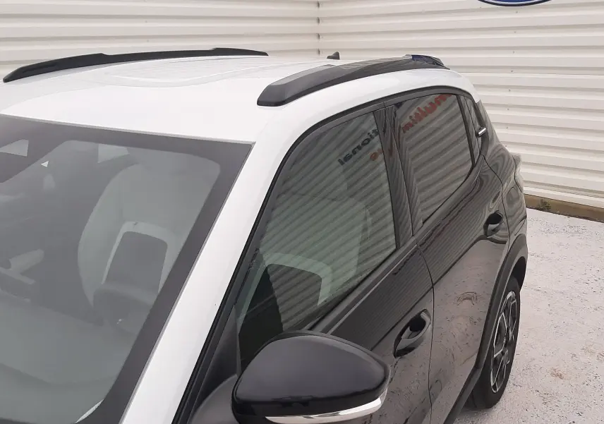 Vue 3/4 avant droit de la Citroën C3 1.2 Turbo 100ch Max noire avec toit blanc et barres de toit noires.