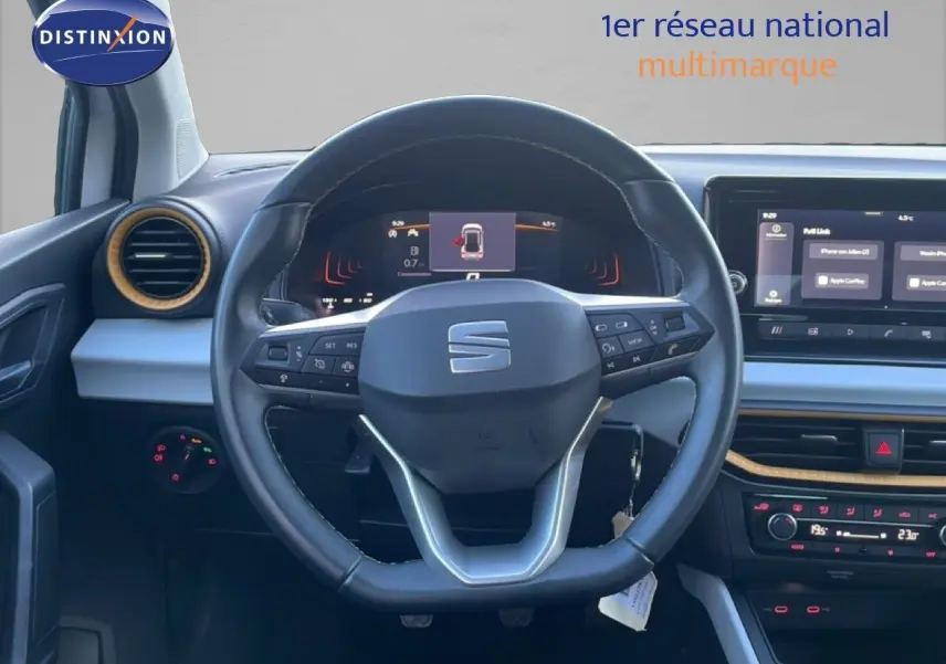 Vue intérieure centrée sur le volant cuir noir et le tableau de bord digital du SEAT Arona blanc toit gris 2025.