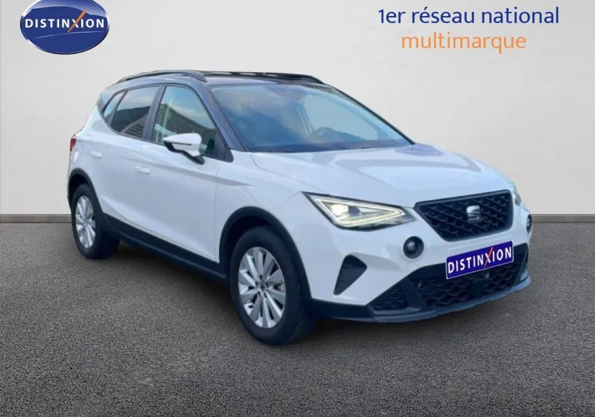SEAT Arona blanc avec toit gris, vue 3/4 avant droit, feux allumés et calandre noire distinctive.