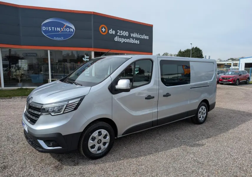 Renault Trafic Fourgon gris Highland en 3/4 avant droit, avec portes latérales vitrées et enjoliveurs 16 pouces.