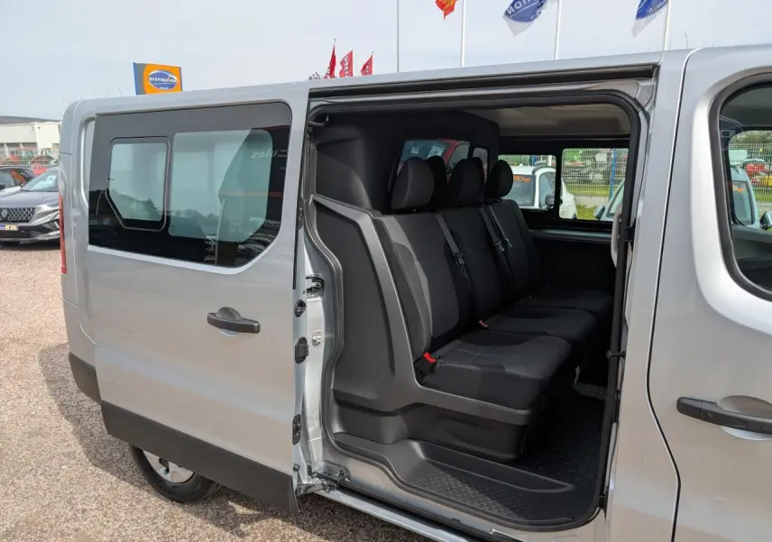 Vue latérale gauche d’un Renault Trafic Fourgon gris avec porte coulissante ouverte dévoilant la banquette arrière 3 places.