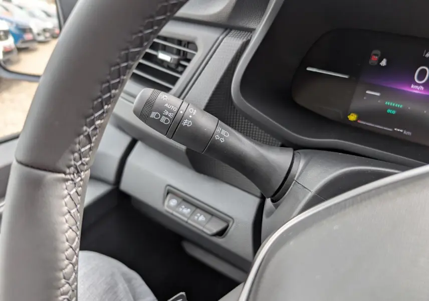 Gros plan sur la manette des feux à gauche du volant dans l’habitacle gris du Renault Trafic Fourgon 2025.