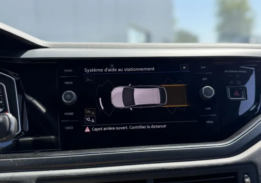 Écran central du Volkswagen Taigo TSI 116 DSG R-Line 2025 montrant l’aide au stationnement avec alerte capot arrière ouvert.
