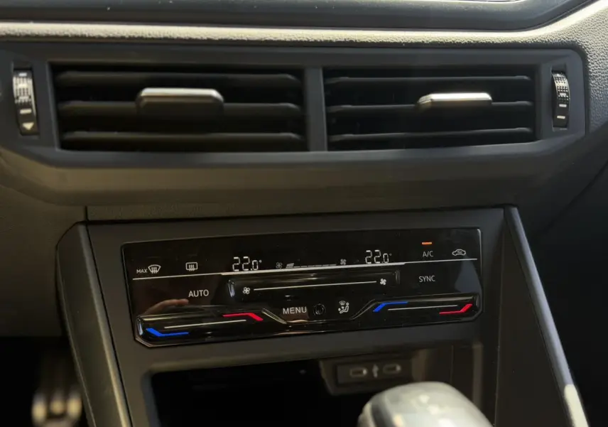 Vue rapprochée du tableau de bord du Volkswagen Taigo argent, mettant en valeur la climatisation automatique bi-zone et les commandes tactiles.