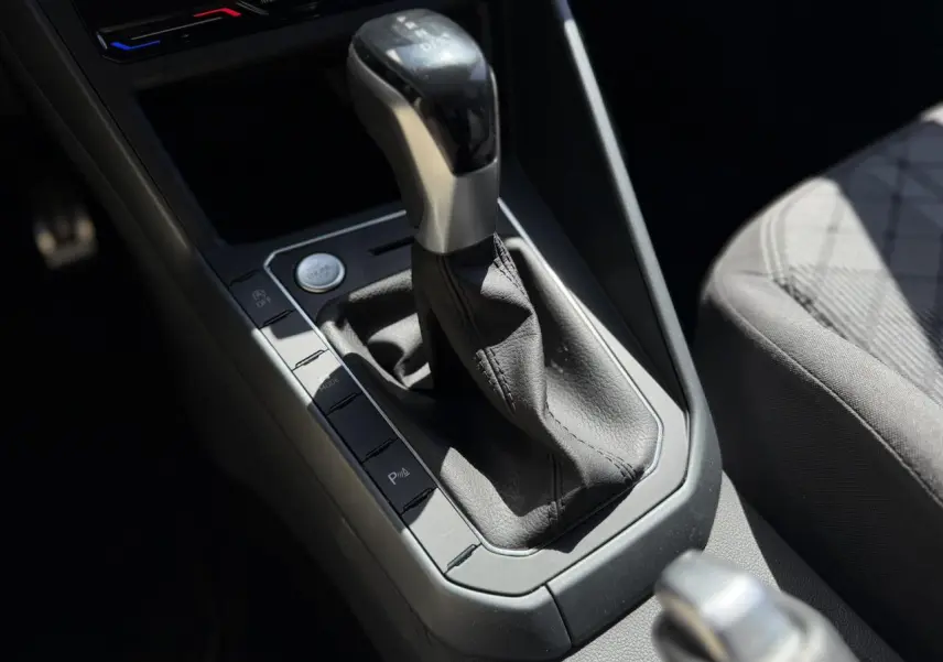 Gros plan sur la console centrale et levier de vitesse automatique du Volkswagen Taigo TSI 116 DSG R-Line, intérieur gris.