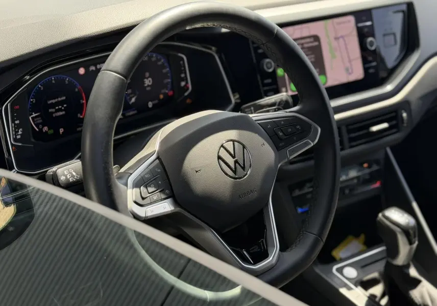 Vue intérieure centrée sur le volant cuir multifonctions et le tableau de bord numérique du Volkswagen Taigo TSI 116 DSG R-Line.