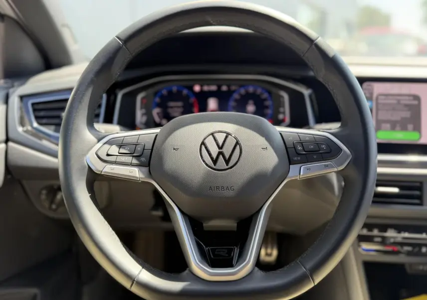 Vue rapprochée du volant cuir multifonctions Volkswagen Taigo R-Line avec logo central et commandes intégrées.