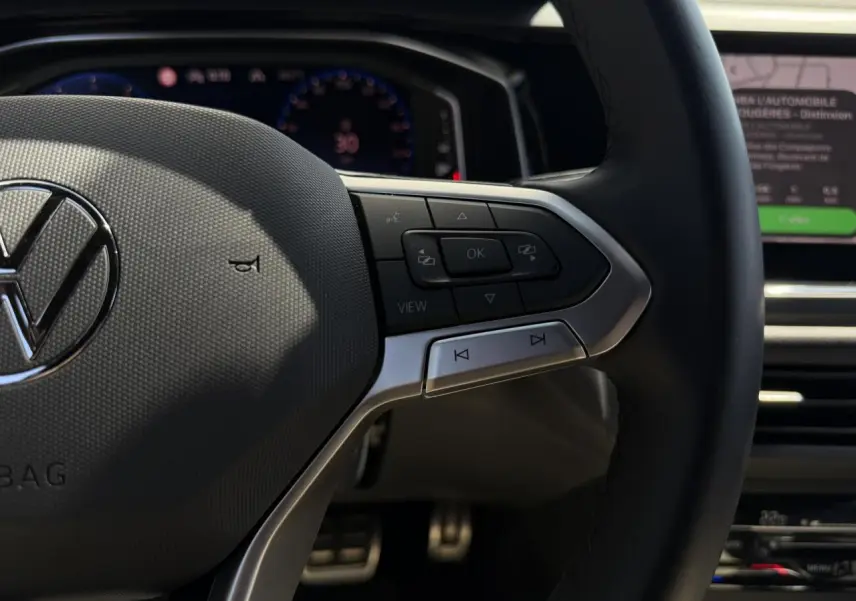 Gros plan sur le volant multifonctions en cuir du Volkswagen Taigo TSI 116 DSG R-Line, avec commandes intégrées.