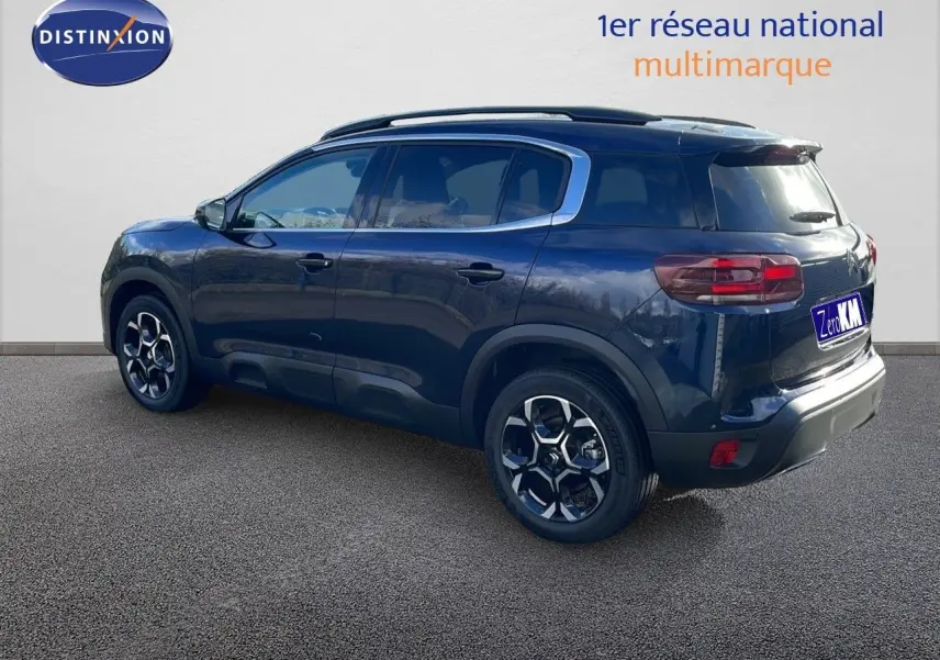 Vue 3/4 arrière droite d'un Citroën C5 Aircross bleu Eclipse Metal avec jantes alliage et barres de toit.