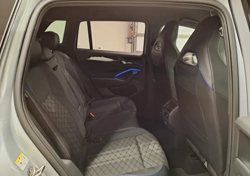 Vue intérieure côté gauche des sièges arrière du Volkswagen Tiguan 2.0 TDI 150 DSG7 R-Line avec surpiqûres bleues.