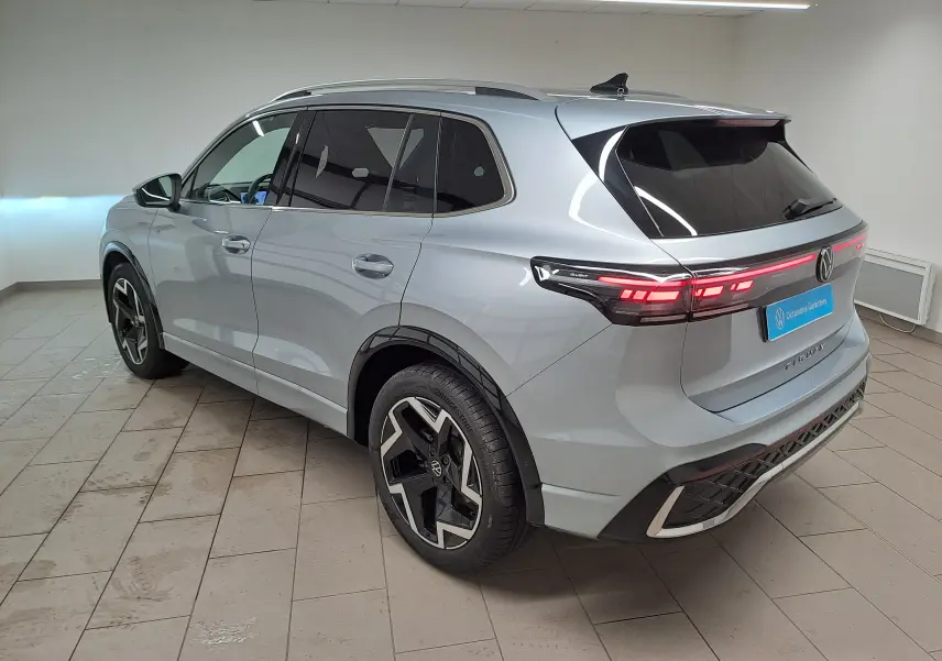 Volkswagen Tiguan 2.0 TDI R-Line argent Dolomite vu 3/4 arrière droit avec feux arrière LED allumés.