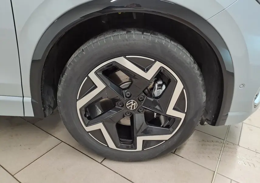 Gros plan sur la roue avant droite du Volkswagen Tiguan 2025 argent Dolomite avec jante R-Line noire et argentée au design géométrique.