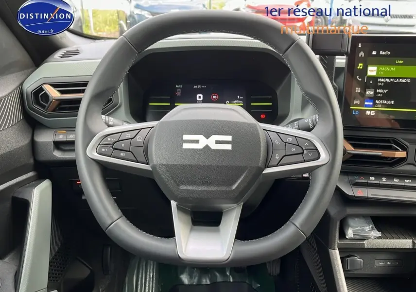 Vue intérieure centrée sur le volant multifonction noir du Dacia Duster 2025 avec tableau de bord numérique et écran tactile.