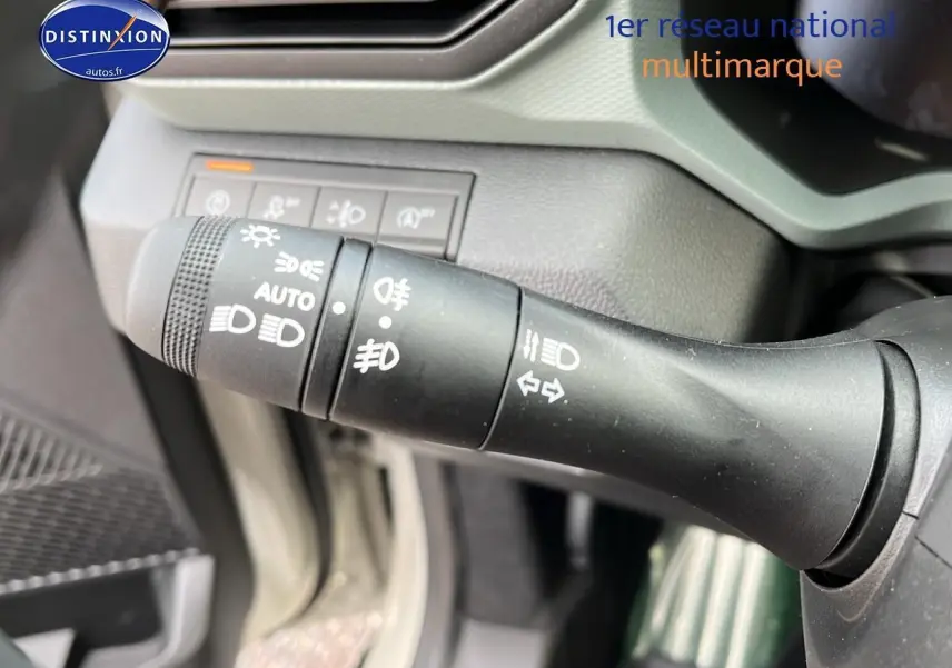 Gros plan sur la commande des feux et clignotants du Dacia Duster 2025, intérieur gris clair et noir.