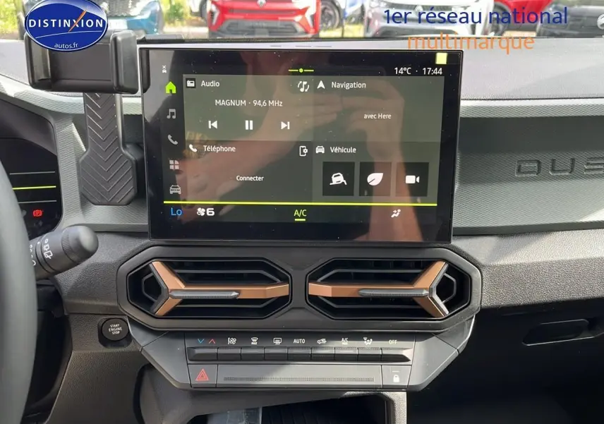 Vue intérieure du tableau de bord du Dacia Duster 2025 avec écran tactile et aérateurs hexagonaux couleur cuivre.
