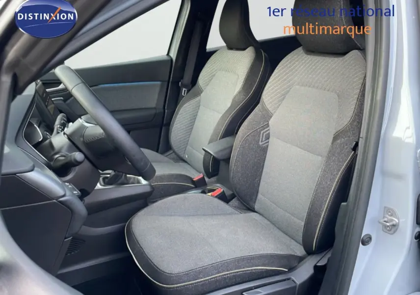 Vue intérieure côté conducteur du Renault Captur 2025, sièges tissu gris avec surpiqûres claires et volant cuir noir.