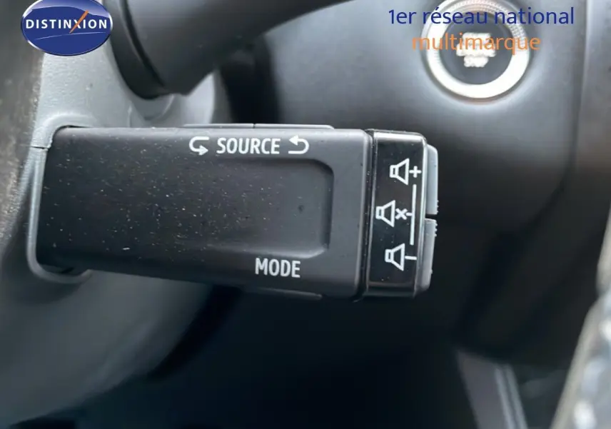 Gros plan sur la commande au volant Renault Captur 2025, bouton source et mode, intérieur noir.