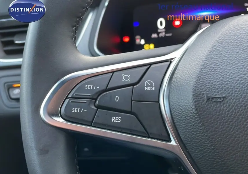 Gros plan sur les commandes au volant noir du Renault Captur 2025, affichage digital en arrière-plan flou.