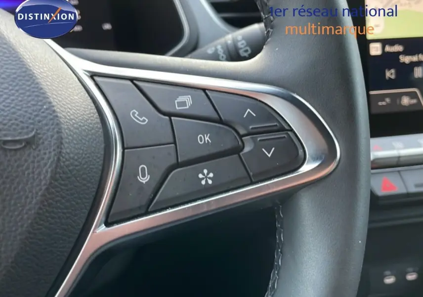 Gros plan sur les commandes multifonctions à gauche du volant cuir noir du Renault Captur gris Rafale métal 2025.