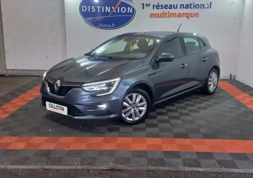 Renault Mégane Business TCe 115 gris foncé vue 3/4 avant droit, phares LED allumés en intérieur showroom.