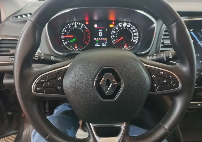 Vue rapprochée du volant multifonctions noir de la Renault Mégane Business 2022 avec tableau de bord digital allumé.