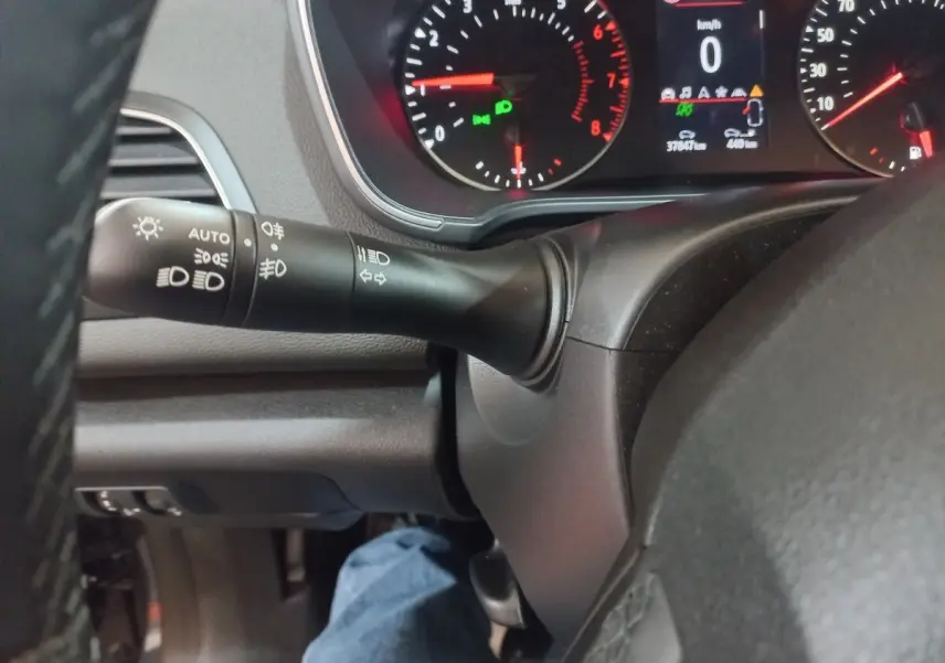 Gros plan sur le commodo gauche et le tableau de bord numérique de la Renault Mégane Business gris foncé, affichage multifonctions allumé.