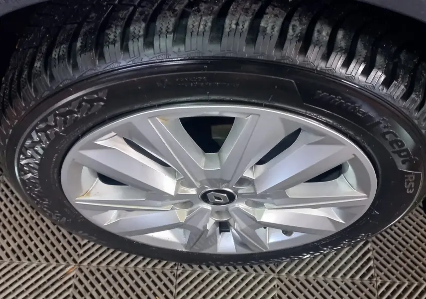 Gros plan sur la roue avant droite d'une Renault Mégane gris foncé, avec jante alliage à plusieurs branches.